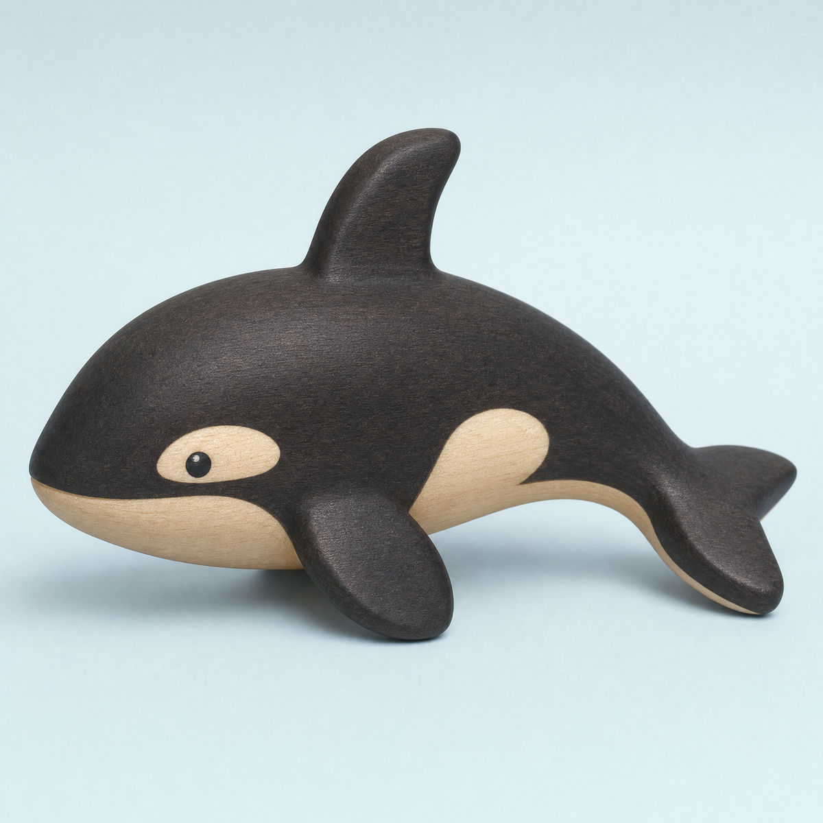 Jorlaxis Orca: a small wooden orca with a dark-stained back and pale belly on a plain pale background