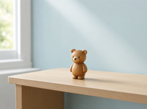 The small wooden bear on a pale oak surface against a duck-egg blue wall